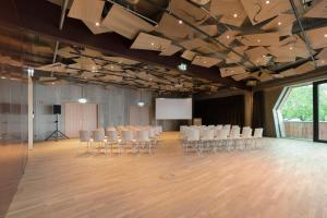 uma sala de conferências com cadeiras brancas e um ecrã em Raphael Hotel Wälderhaus em Hamburgo