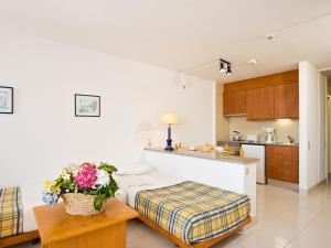 a kitchen with a bed and a table with flowers on it at Apartamentos Edificio Albufeira - Alojamento Local in Albufeira