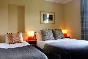 a bedroom with two beds and two lamps on tables at Camus Bhan in Ballachulish