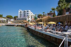 a beach with chairs and umbrellas next to the water at Marti Beach Hotel in Kuşadası