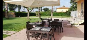 a patio with tables and chairs and an umbrella at La casa del Moro in Sabaudia