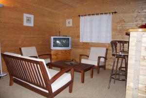 ein Wohnzimmer mit einem TV, Stühlen und einem Tisch in der Unterkunft chalet Porticcio Corse in Fontanaccio