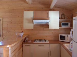 eine Küche mit weißen Schränken, einem Herd und einer Mikrowelle in der Unterkunft chalet Porticcio Corse in Fontanaccio