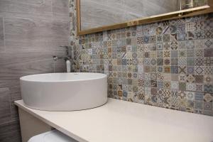 a bathroom with a white sink and a tiled wall at Pearl apartment in Kutaisi in Kutaisi +12 photos
