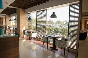 a restaurant with tables and chairs and a large window at Novanta Jamshedpur in Jamshedpur
