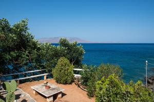 a picnic table sitting on the side of the ocean at apartment over the sea Private place to swim in Ravdhoúkha