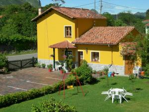 ein gelbes Haus mit einem Spielplatz im Hof in der Unterkunft Camangu-Estudio in Ribadesella