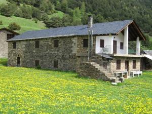 una casa de piedra en un campo de flores amarillas en Borda Cortals de Sispony en La Massana