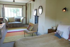 a bedroom with a bed and a chair and a mirror at Tinsmiths House in Aylsham