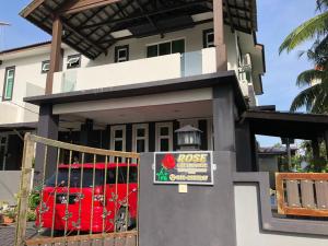 dom z czerwonym samochodem zaparkowanym przed nim w obiekcie Rose Guest House w mieście Kota Bharu