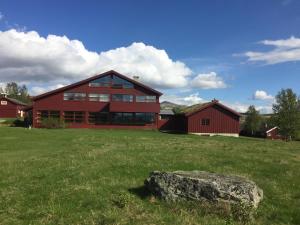 a large red house with a rock in a field at Høvringen Høgfjellshotell in Høvringen