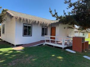 una pequeña casa blanca con techo de hierba en Cabañas Punto Verde, en La Serena