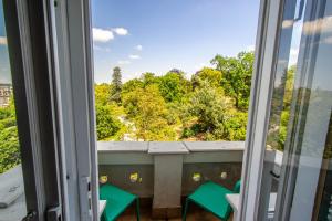 a window with two green chairs looking out at a forest at Garden ApartHotel in Prague