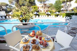 un tavolo con cibo accanto a una piscina di Hotel Ambassador Meuble a Lignano Sabbiadoro