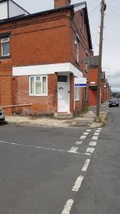 a brick building with a white door on a street at TUii Appart, Cleveleys Road Holbeck in Leeds