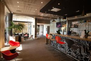 a restaurant with a bar with red chairs at ibis Marseille Provence Aéroport in Marignane