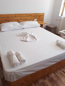 uma cama branca com dois guardanapos e toalhas em Beleris Rooms em Himare