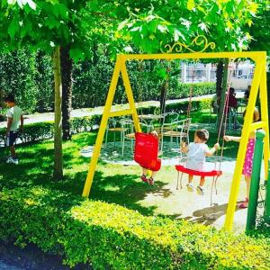 dos niños jugando en un columpio en un parque en Hotel Ambasador Garden, en Lezhë