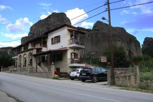 a house on the side of a mountain with cars parked in front at Guesthouse Vavitsas in Kalabaka