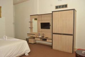 a bedroom with a bed and a cabinet with a television at Hotel Assyifa Tanjungbalai in Tanjungbalai