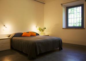 a bedroom with a bed with orange pillows and a window at Corte La Volta in Piacenza