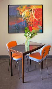 una mesa de madera con sillas naranjas y un jarrón con flores en Corte La Volta en Piacenza