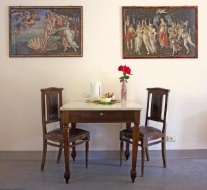 una mesa con dos sillas y un jarrón de flores. en Corte La Volta en Piacenza