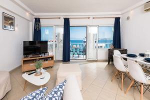 a living room with a couch and a tv and a table at Promenade Sea View Apartment in Limenas