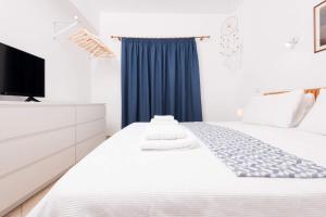 a bedroom with a white bed and a tv at Promenade Sea View Apartment in Limenas