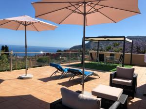 eine Terrasse mit 2 Sonnenschirmen, 2 Stühlen und Tischen in der Unterkunft Villa Manzanera in Calpe