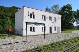 a white building with a sign in front of it at Remiza w Starej Papierni in Łapino