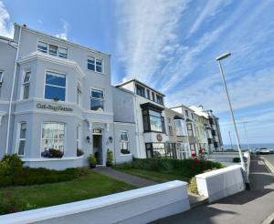 a white building on a street next to the ocean at Cul-Erg House & Kitchen in Portstewart