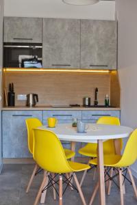uma cozinha com uma mesa branca e cadeiras amarelas em Apartamenty Natalia - bezpłatny parking em Krynica-Zdrój