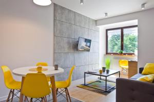 uma sala de estar com uma mesa e cadeiras amarelas em Apartamenty Natalia - bezpłatny parking em Krynica-Zdrój