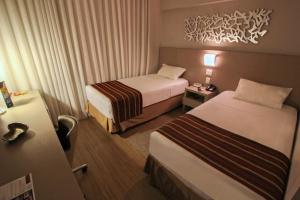 um quarto de hotel com duas camas e uma mesa em Hotel Beaga Convention Expominas by MHB em Belo Horizonte