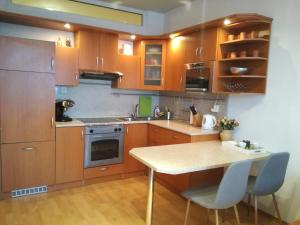 a kitchen with wooden cabinets and a table with chairs at Cozy apartment btw centre and airport - Private host - No invoice in Bratislava