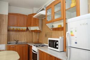 uma cozinha com armários de madeira e um micro-ondas branco em Mellis 1 em Cluj-Napoca