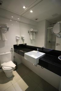 a bathroom with a sink and a toilet and a mirror at Hotel Beaga Convention Expominas by MHB in Belo Horizonte