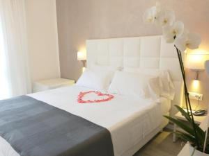 a bedroom with a white bed with a red heart on it at Hotel Acapulco in Lignano Sabbiadoro