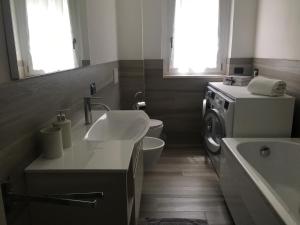a bathroom with a sink and a washing machine at Appartamento tra lago e cielo in Como