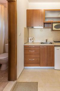 a small kitchen with wooden cabinets and a sink at Hotel Genada in Sveti Vlas