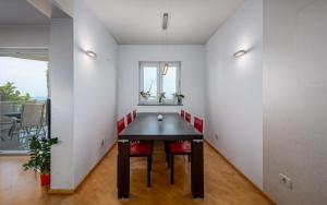 uma sala de jantar com uma mesa preta e cadeiras vermelhas em RIVA house with apartment em Crveni Vrh