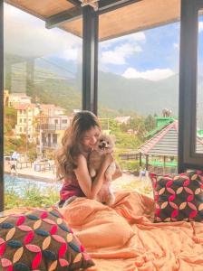 a woman sitting on a bed holding a teddy bear at Bách Xanh House. Nhà Gác Lửng in Vĩnh Phúc