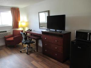 a hotel room with a desk with a television and a chair at Travel Inn and Suites in Lakehurst