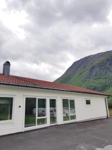 un bâtiment blanc avec une montagne en arrière-plan dans l'établissement Saltvold Leilighet nr 2, à Røldal