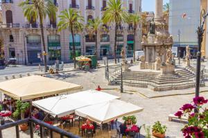 uma praça da cidade com mesas e guarda-sóis e uma fonte em I Balconi di San Domenico em Palermo