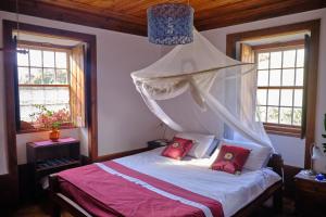 a bedroom with a canopy bed with red pillows at A Charming , Traditional Cottage at Quinta da Ribeira in Vila Nova de Poiares
