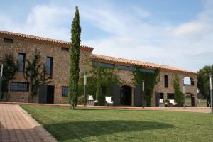 a large brick building with a green yard at Hotel Mas Oliveres Pla de Palau in Llers