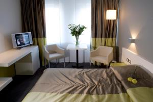 ein Krankenhauszimmer mit einem Bett, zwei Stühlen und einem TV in der Unterkunft Parkhotel Roeselare in Roeselare