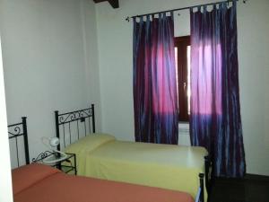 サン・ジョヴァンニ・ア・ピーロにあるVilla Anna Mariaのベッドルーム1室(ベッド2台付)、紫色のカーテン付きの窓が備わります。